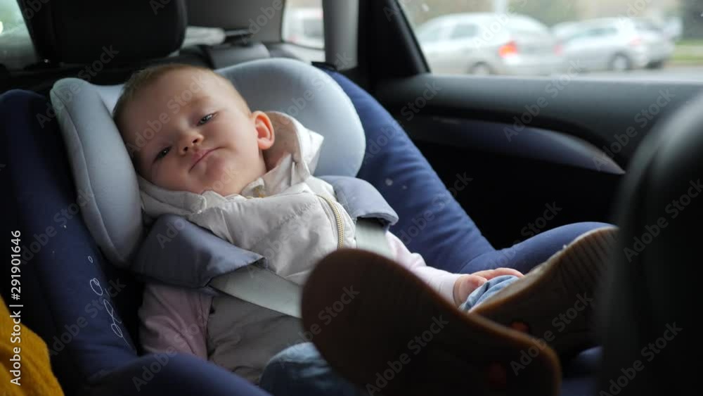 Baby girl safety in a car sit fastened in child seat while a parent carry her in a city Baby girl safety in a car sit fastened in child seat while a parent carry her in a city