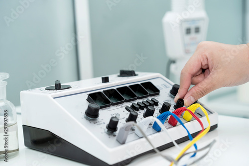 close up hand of doctor using electrical stimulator while or undergoing acupuncture treatment. Concept of Traditional Chinese Medicine. TENS (Transcutaneous Electrical Nerve Stimulation)