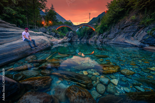 Tourist enjoys sunset at a river near stone bridge in Lavertezzo, Switzerland photo