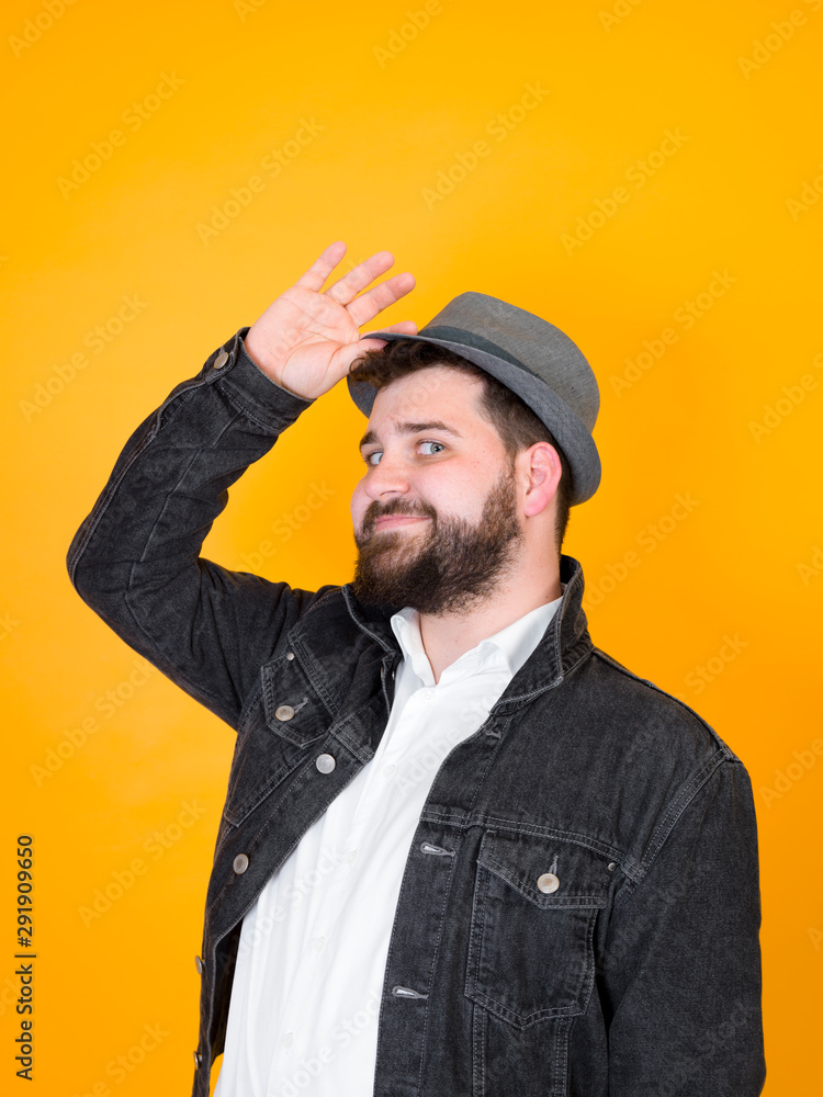 cool man with hat and black beard is posing in front of yellow, orange background cool man with hat and black beard is posing in front of yellow, orange background