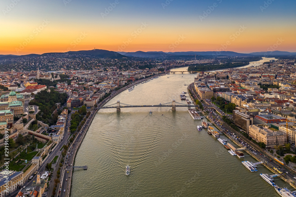Budapest, Hungary - Aerial drone view of Budapest at sunset with clear sky, Buda Castle Royal Palace, Szechenyi Chain Bridge and sightseeing boat on River Danube