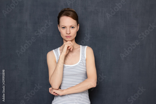 Portrait of serious focused young woman propping head with hand
