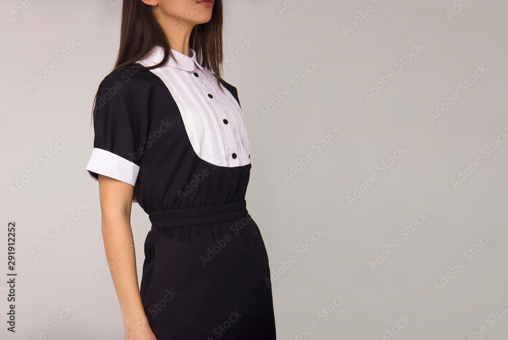 close-up of young teacher with long brunette hair in black stylish dress which is standing in profile on the white wall background. education fashion concept, free space on right side close-up of young teacher with long brunette hair in black stylish dress which is standing in profile on the white wall background. education fashion concept, free space on right side