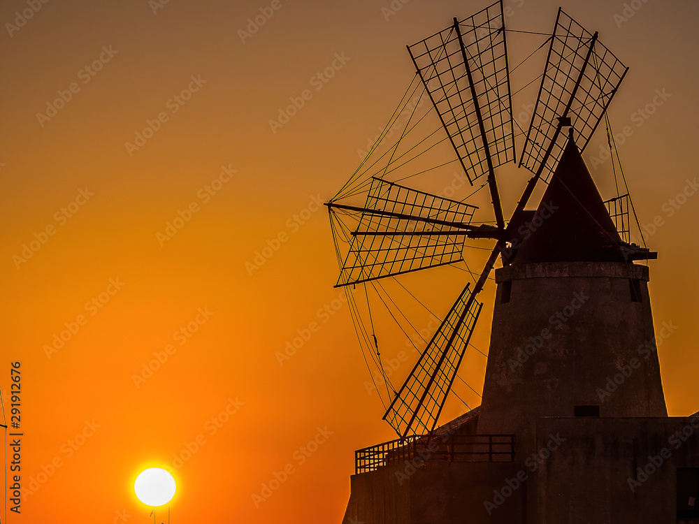 Sunset .Windmills Trapani Sicily .The salt from these marshes is considered Italy’s finest and has been big business for centuries; today, only a cottage industry remains