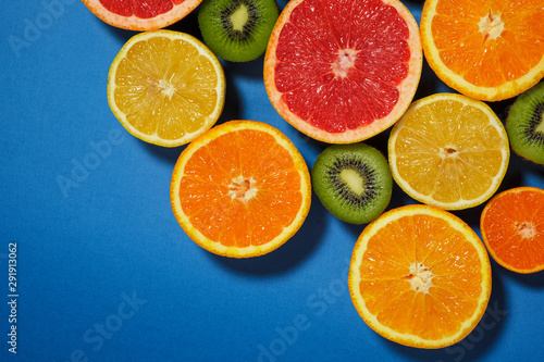 Assortment of various cut raw fruits on blue background, copy space