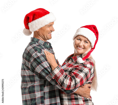 Portrait of happy mature couple in Santa Claus hats on white background