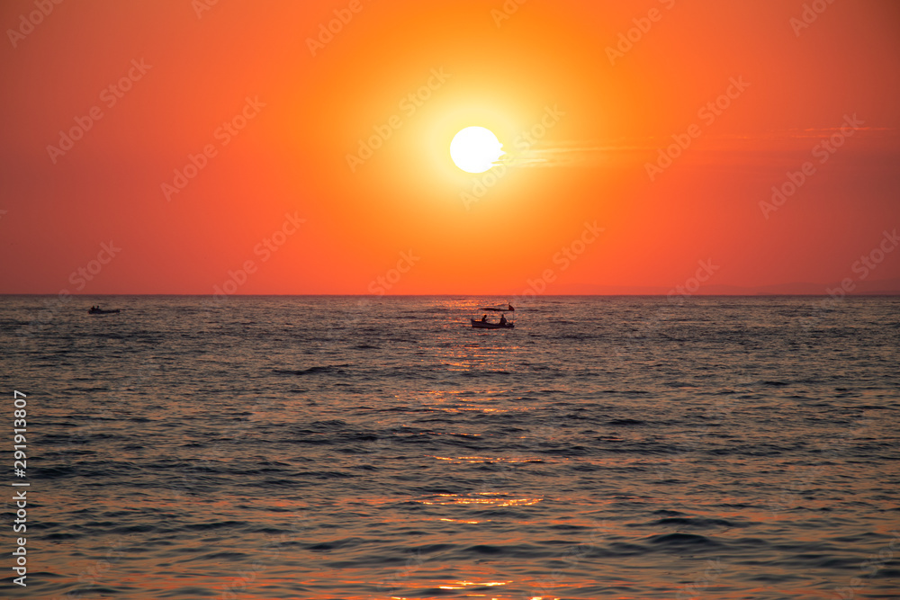 Boat at sunset in a sea during a beautiful colorful golden hour.
