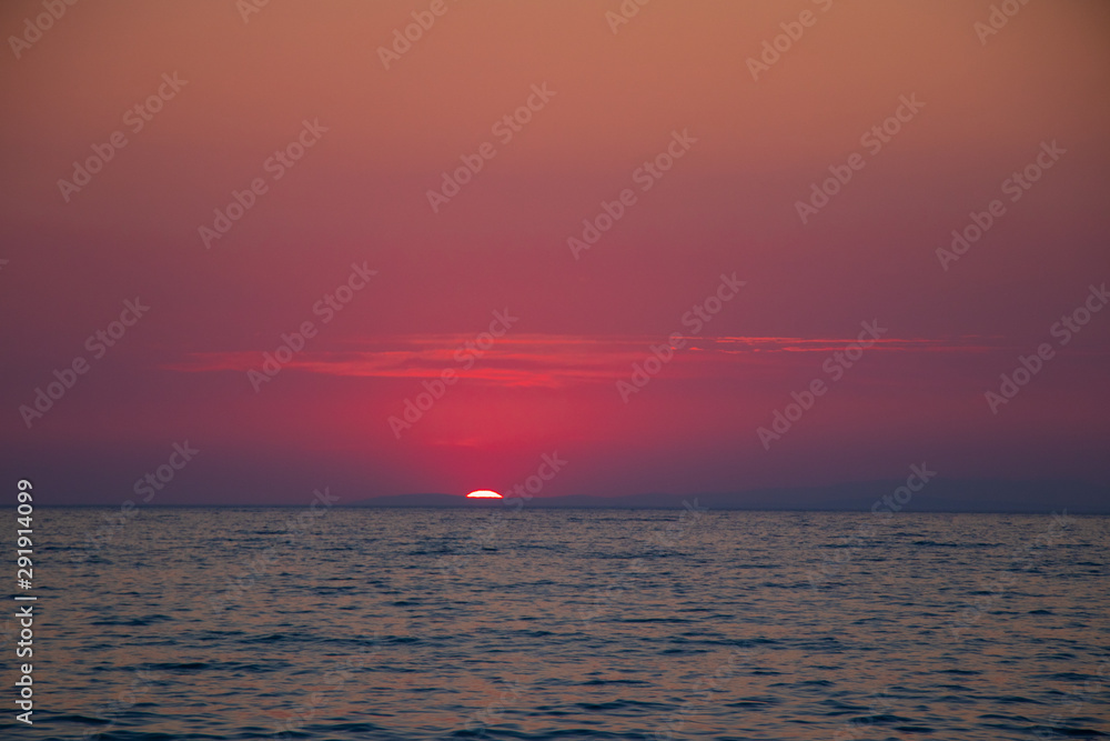 Sunset at sea during a beautiful golden hour. Landscape of the sun setting on the horizon.