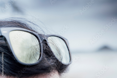 sunglasses over head enjoying summer sun , light grey background
