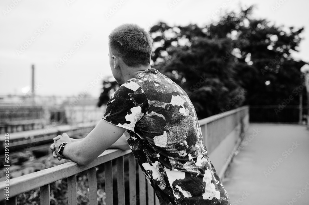 Fototapeta premium Lifestyle portrait of handsome man posing on the street of city and looking at train station.