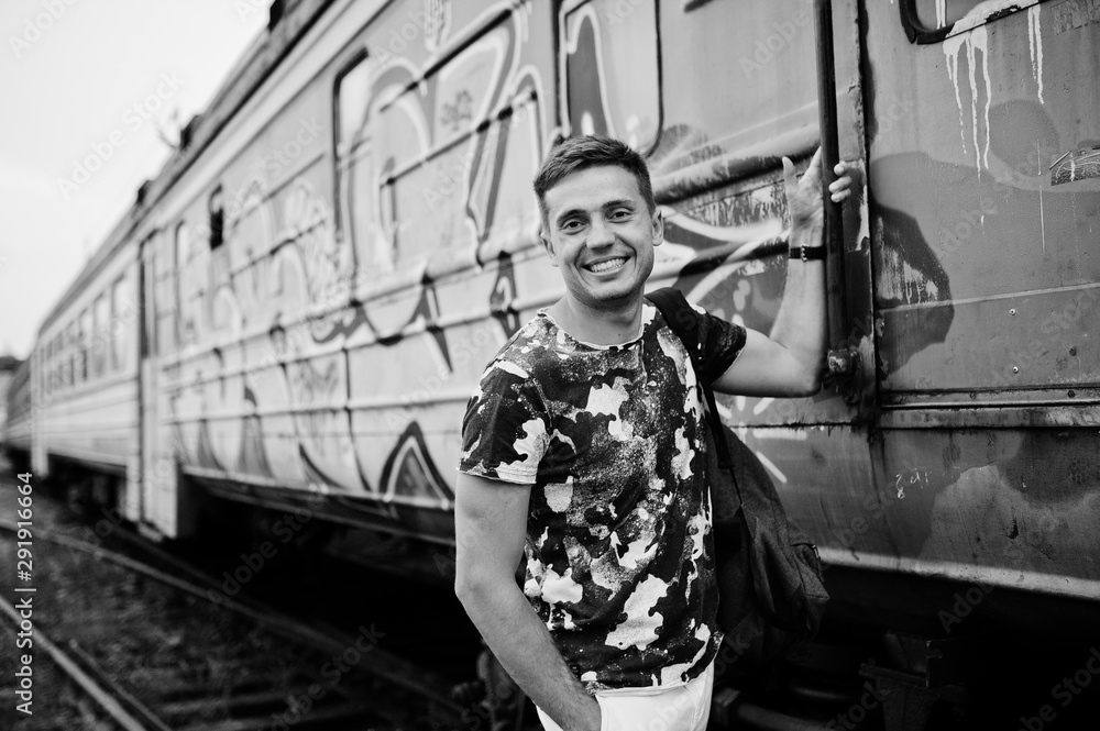 Lifestyle portrait of handsome man with backpack posing on train station.