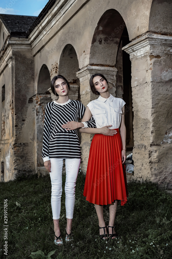 Outdoor fashion portrait of two young beautiful women wearing fashionable clothes posing on the street