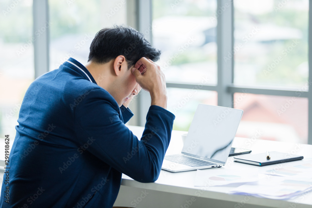 Stressed businessman worked with laptop computer and having a headache after business losses In the office room background. Stressed businessman worked with laptop computer and having a headache after business losses In the office room background.