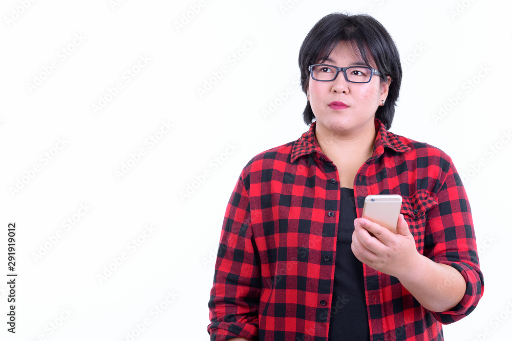 Beautiful overweight Asian hipster woman thinking while using phone Beautiful overweight Asian hipster woman thinking while using phone