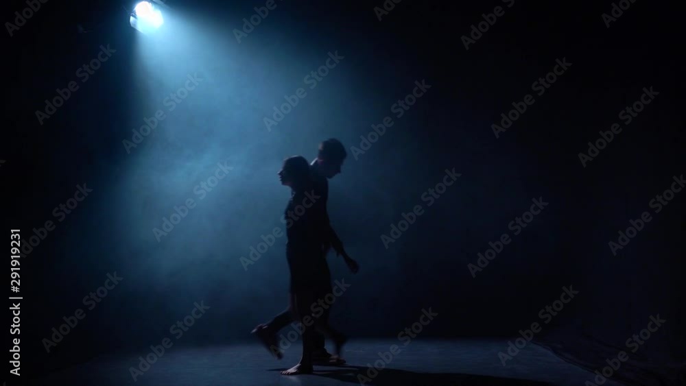 Sexy couple dance musical with acrobatic movement at dark studio in smoke under spotlight, slow motion. Sexy couple dance musical with acrobatic movement at dark studio in smoke under spotlight, slow motion.