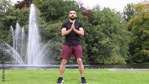 Man doing curtsy lunge in park near fountain