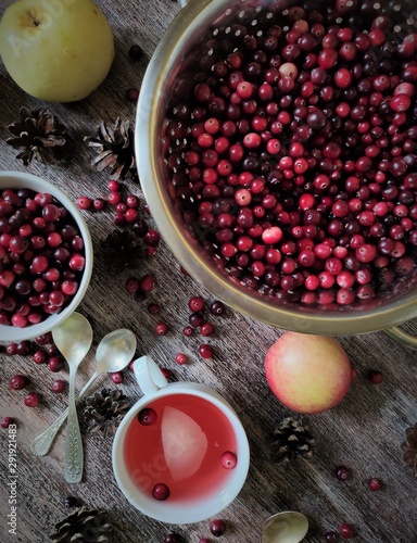 Cranberries Cranberries in a ceramic and metal bowl and saucepan, Apple compote in a white Cup, teaspoon, drink, pine cones, berry decor, autumn harvest, top view, flatlay layout