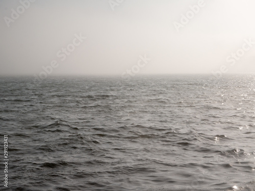 gray or grey sea and blue sky covered with mist or fog