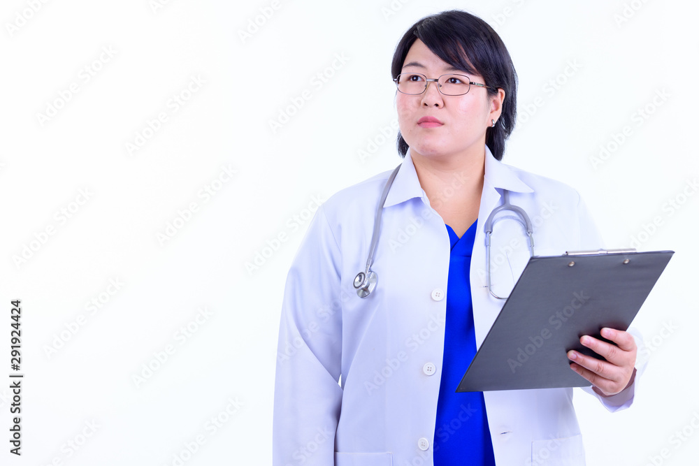 Beautiful overweight Asian woman doctor thinking while holding clipboard Beautiful overweight Asian woman doctor thinking while holding clipboard