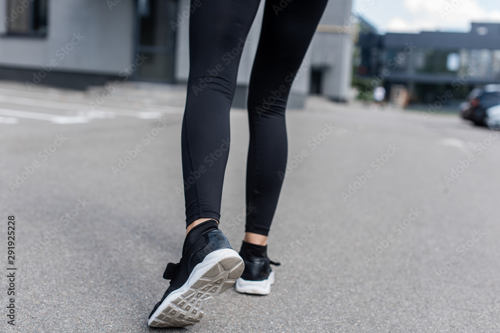 cropped view of sportswoman in black sneakers on street