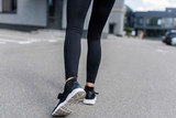 cropped view of sportswoman in black sneakers on street