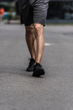 partial view of sportsman in black sneakers walking on street