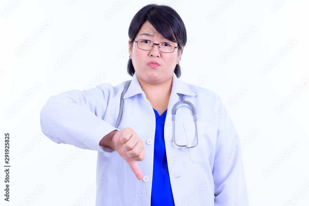 Stressed overweight Asian woman doctor giving thumbs down Stressed overweight Asian woman doctor giving thumbs down