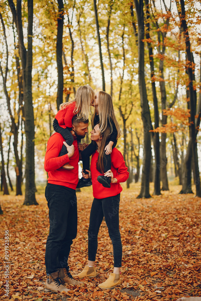 Family in a autumn park. Woman in a red sweater. Cute childrens with parents Family in a autumn park. Woman in a red sweater. Cute childrens with parents