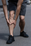 partial view of sportsman in black sneakers with leg pain on street
