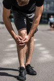 partial view of sportsman with knee pain on street