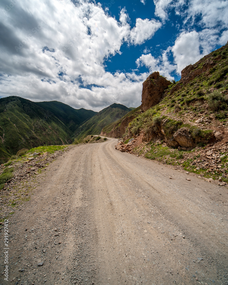 Mountain dirt road with no guard rail or side protection high in the Himalayas mountains disappears after a bend