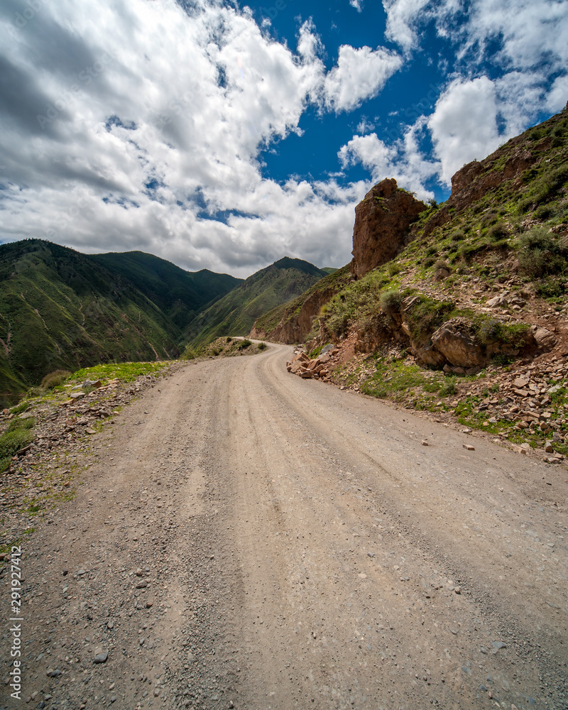 Mountain dirt road with no guard rail or side protection high in the Himalayas mountains disappears after a bend Mountain dirt road with no guard rail or side protection high in the Himalayas mountains disappears after a bend
