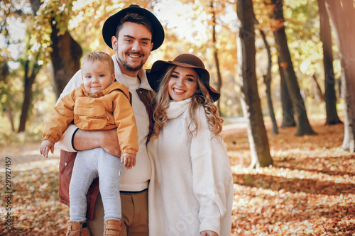 Family have fun in a autumn park. Cute blode in a white sweater. Parents with little son