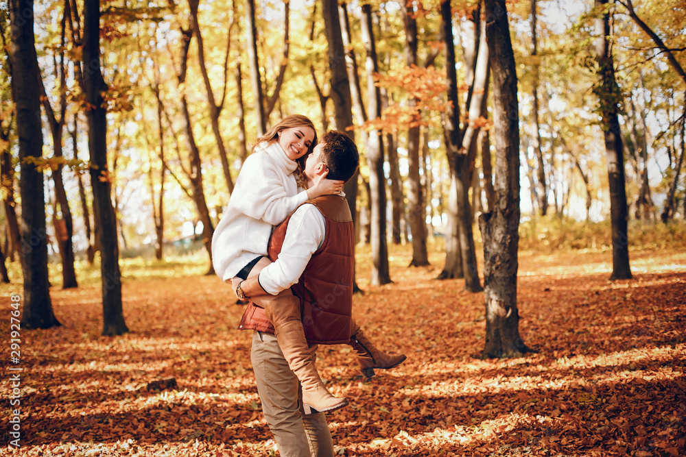 Fototapeta premium Couple have fun in a autumn park. Cute blode in a white sweater.