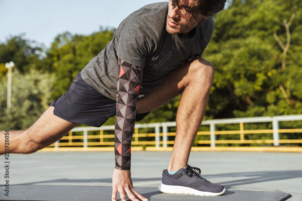 Photo of athletic unshaven man doing exercises on mat Photo of athletic unshaven man doing exercises on mat