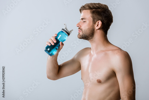 shirtless bearded sportsman holding sport bottle isolated on grey