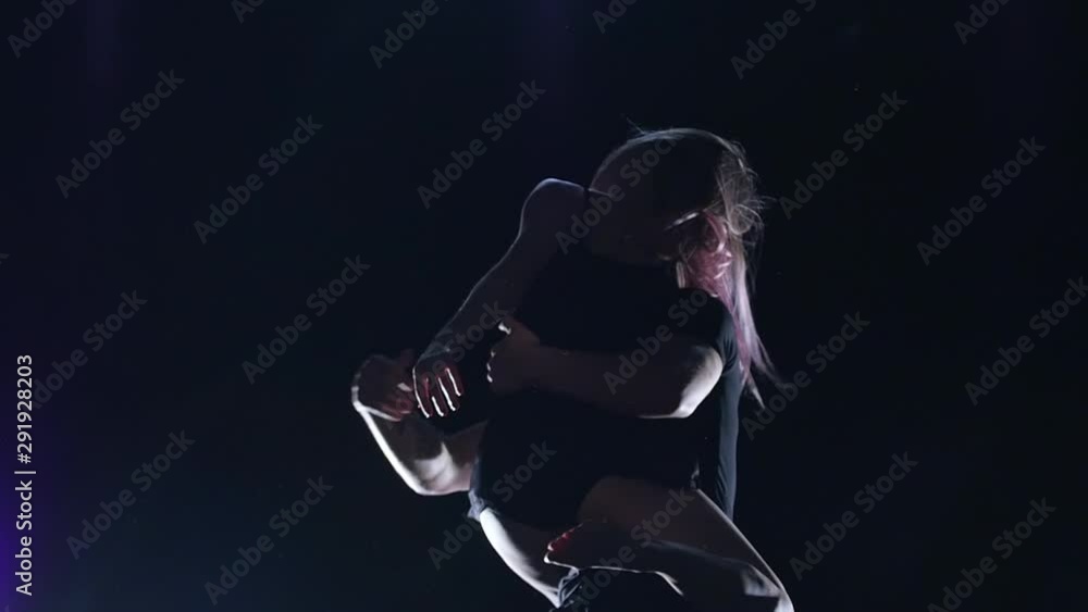 Two modern dancers are dancing passionate contemp on dark studio against spotlights, slow motion. Close up Two modern dancers are dancing passionate contemp on dark studio against spotlights, slow motion. Close up
