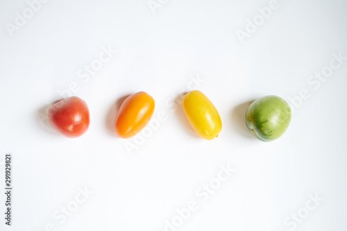 Red, green and yellow tomatoes in line on white background, flat view