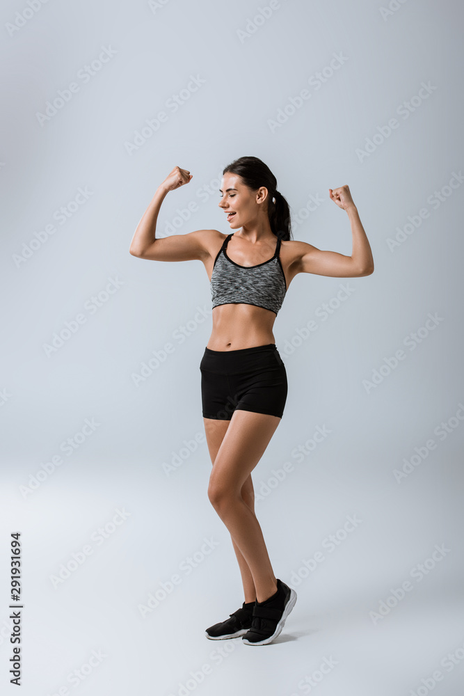 full length view of smiling sportswoman on grey full length view of smiling sportswoman on grey
