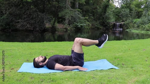 Man doing reverse crunch in park