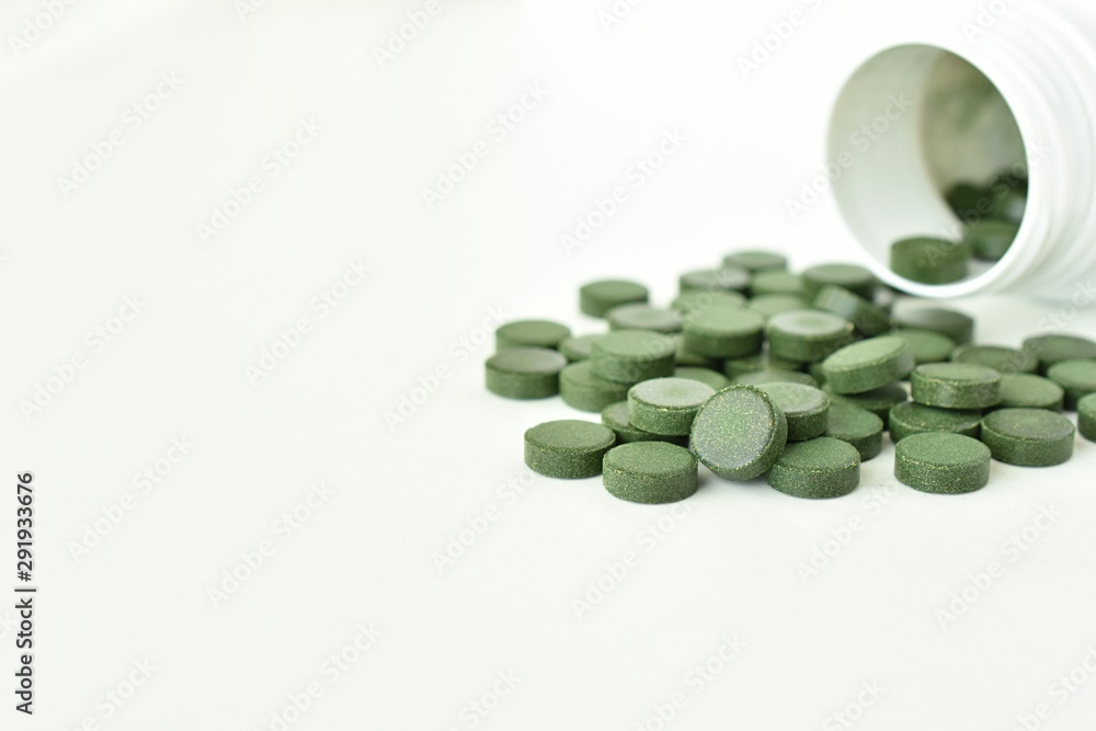 Spirulina tablets close up view and white bottle, copy space. Spirulina tablets close up view and white bottle, copy space.