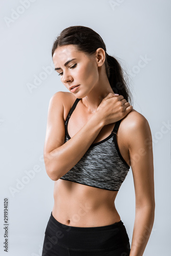 attractive sportswoman with neck pain isolated on grey © LIGHTFIELD STUDIOS