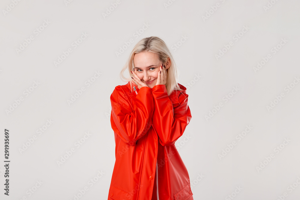 Smiling blond girl in a red raincoat with hood isolated over white background. It?s starting to rain. Smiling blond girl in a red raincoat with hood isolated over white background. It?s starting to rain.