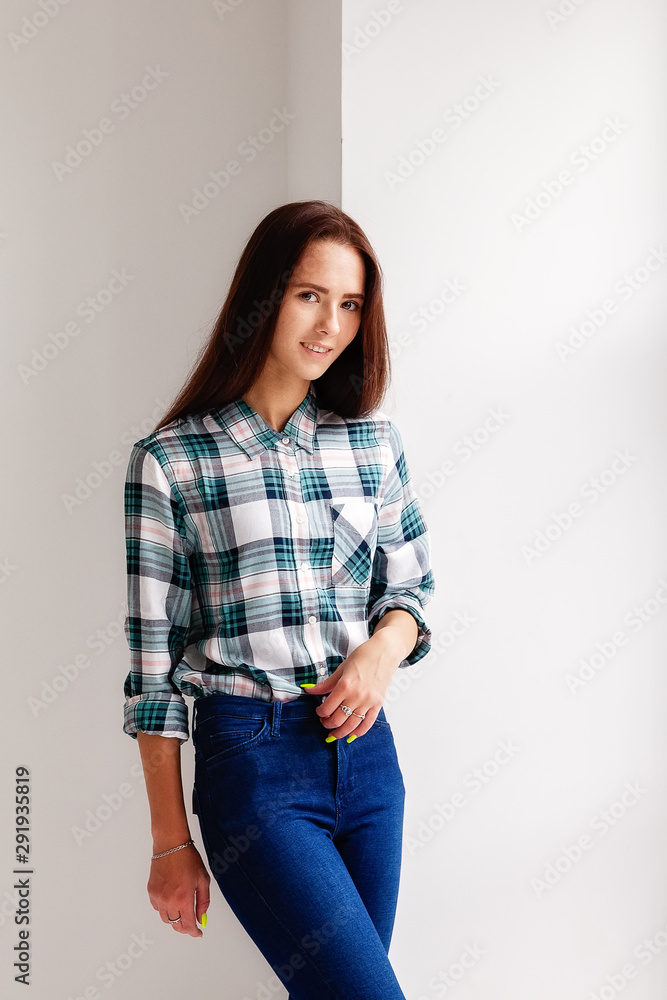 Girl in plaid shirt and jeans is on white background Girl in plaid shirt and jeans is on white background
