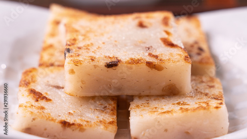 Delicious turnip cake, Chinese traditional local dish radish cake in restaurant with soy sauce and chopsticks, close up, copy space.