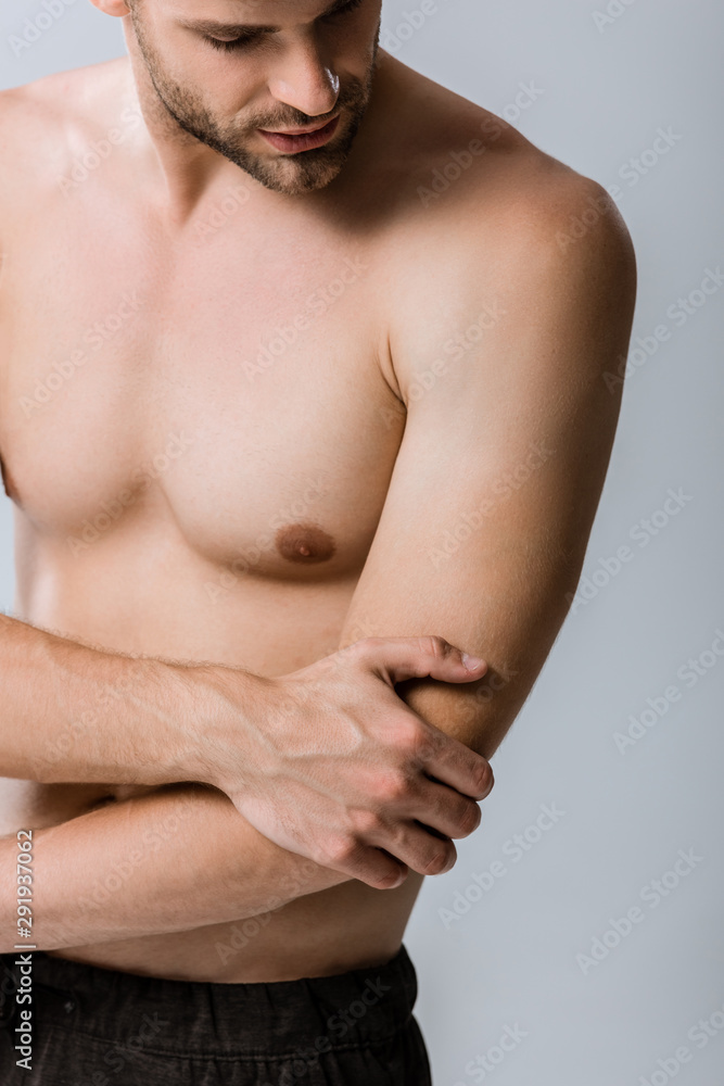 partial view of shirtless man with pain in elbow isolated on grey