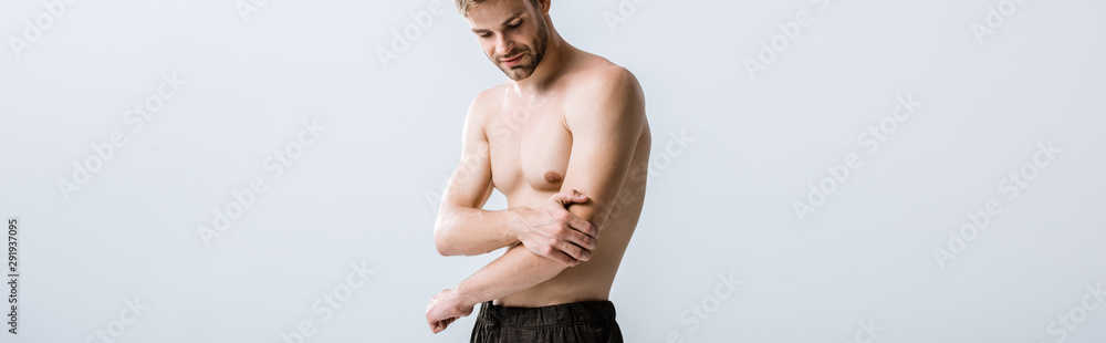 panoramic shot of shirtless man with pain in elbow isolated on grey