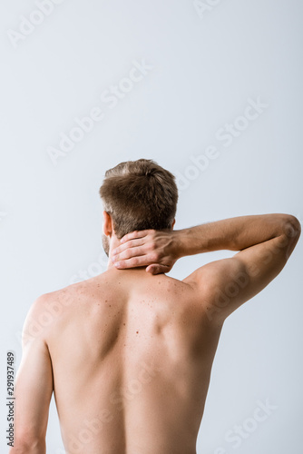 back view of shirtless man with neck pain isolated on grey