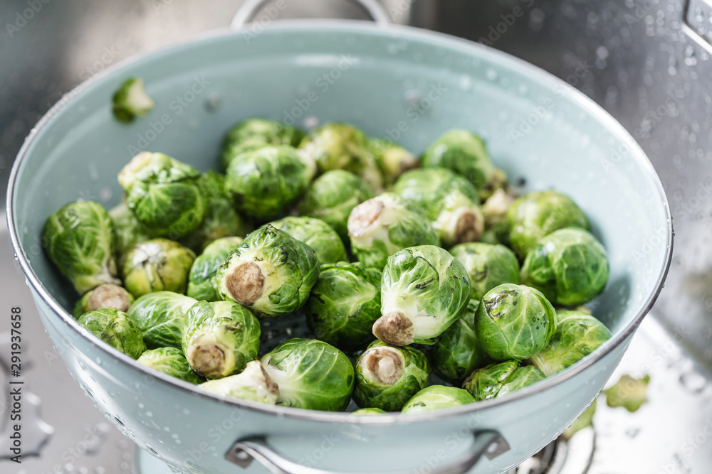 washing raw Brussels sprouts in kitchen sink washing raw Brussels sprouts in kitchen sink
