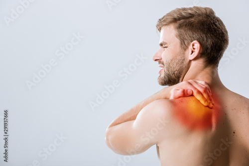 shirtless bearded man with pain in shoulder isolated on grey